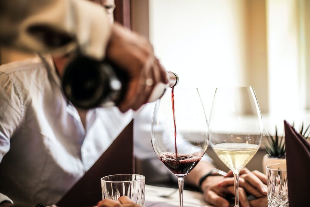 Crop man pouring red wine in glass in restaurant